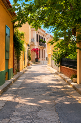 Petite rue calme du quartier de Plaka à Athènes bordée de maisons colorées et d'arbres méditerranéens.