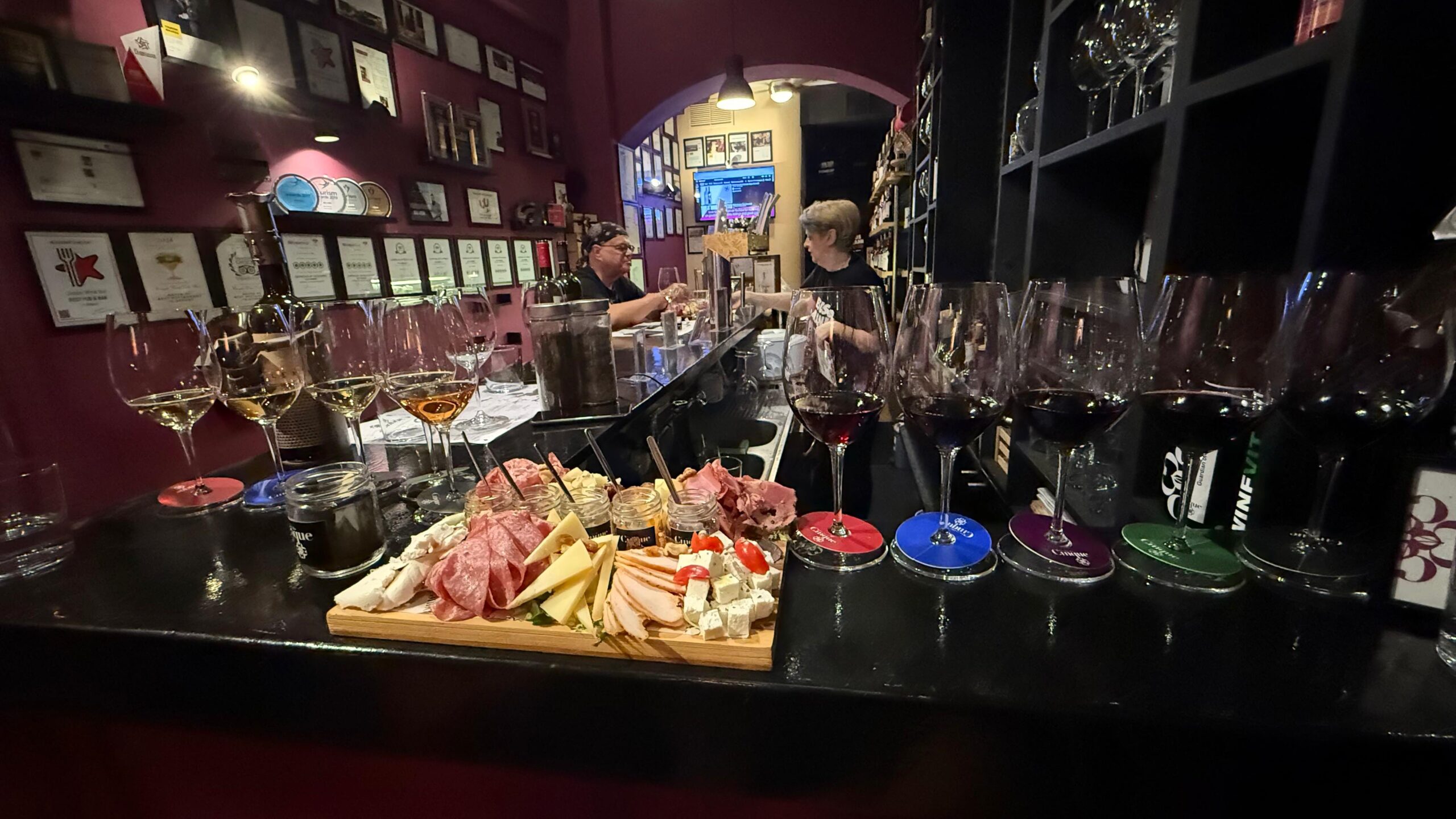 Planche de charcuteries et fromages accompagnée de plusieurs verres de vin lors d'une dégustation dans un établissement d'Athènes.